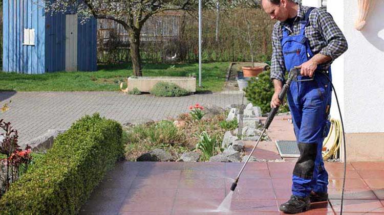 A man pressure washing a patio.